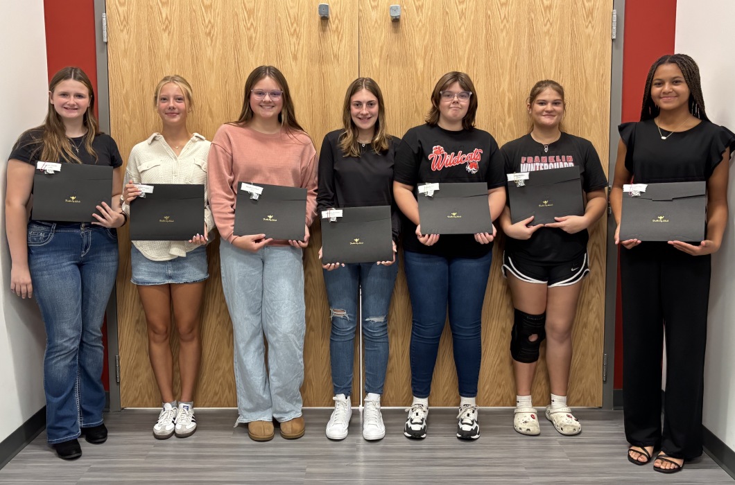 Seven students holding student achievement certificates.